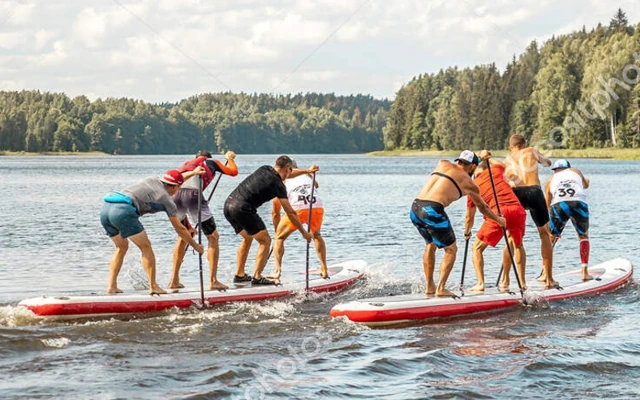 Deux équipes de quatre hommes effectuent une course sur des paddles géants