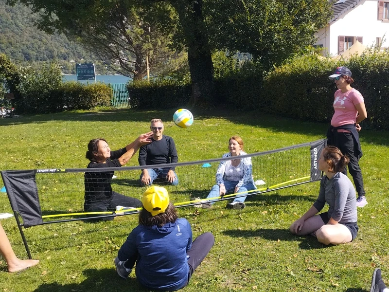 Un groupe d'adultes joue un match de volley dans l'herbe